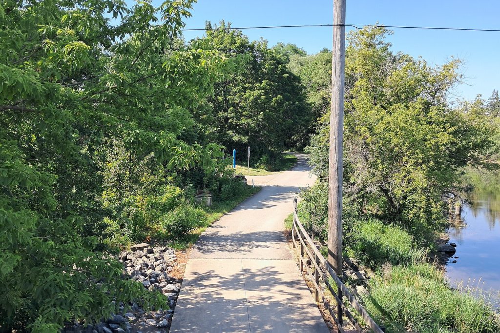 A gravel trail running south under summer trees beside a utility line along the Des Plaines River Trail