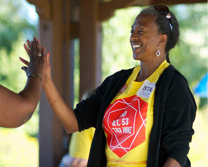 A smiling volunteer in a No Rt. 53 Tax Hike apron gives a high five